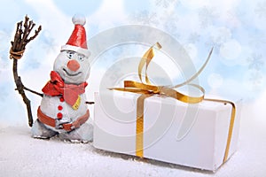 Christmas snowman in the snow with giftbox against the backdrop