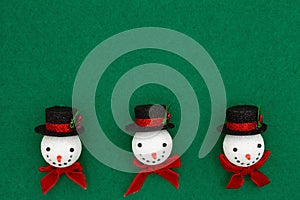 Christmas snowmen with top hats on green felt background