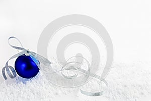 Christmas snowy background with blue ornament with silver ribbon