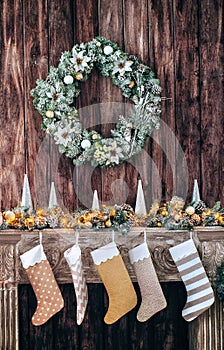 Christmas socks on decorated fireplace, background of a wooden wall with a green wreath