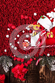 Christmas socks full of candy and sweets on red fleecy background. Flat lay. Copy space.