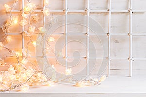 Christmas soft home decor with lights burning on a white wooden background.