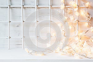 Christmas soft home decor with lights burning on a white wooden background.
