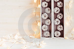 Christmas soft home decor of silver apples and lights burning in boxes on a wooden white background.