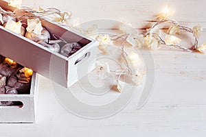 Christmas soft silver apples and lights burning in boxes on a wooden white background.