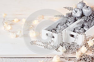 Christmas soft silver apples and lights burning in boxes on a wooden white background.