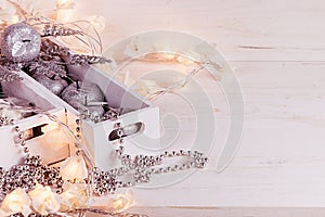 Christmas soft silver apples and lights burning in boxes on a wooden white background.