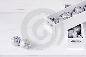 Christmas soft silver decorations in white boxes on a white wooden background.