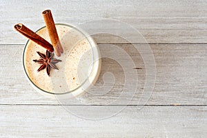 Christmas spiced eggnog in a glass, top view on gray wood