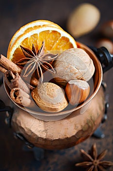 Christmas spices, nuts and dried oranges on a wooden background.