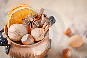 Christmas spices, nuts and dried oranges on a wooden background.