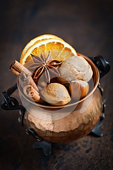 Christmas spices, nuts and dried oranges on a wooden background.