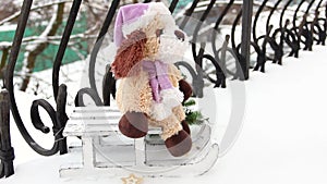 Christmas spirit. A soft toy on a sleigh. Christmas decorations in the snow