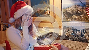 Christmas spirit. Young caucasian woman receiving a gift with a shy smile