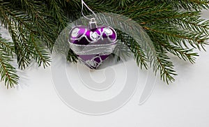 Christmas spruce decoration toys shaped like a heart hanging on a tree branch. Green wood background. Copy space. Concept of