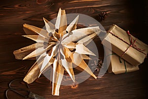 Christmas star made from paper bags, on a wooden table with gift boxes in craft paper. Reuse concept. Zero waste New