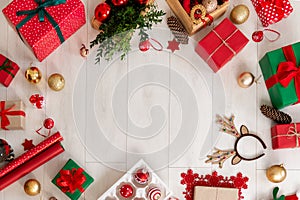Christmas still life border. Presents, decorations, wrapping paper and ornaments on wooden floor. Top view.