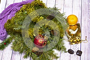 Christmas still life. branches of green spruce with ornaments, a bag of gold, tangerine and candy on a light tree background