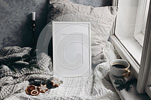 Christmas still life. Candle in golden candleholder. White picture frame mockup. linen pillow near window. Moody