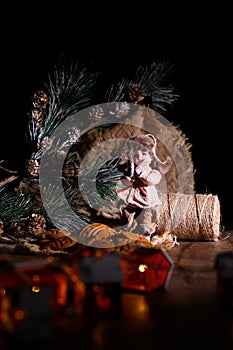 Christmas still life. A doll in warm clothes, ate branches with cones, gingerbread cookies