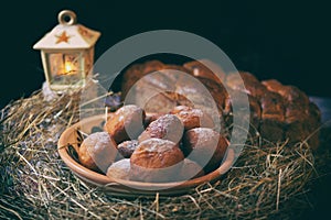 Christmas still life. Donuts and kalach on the table covered with hay