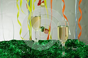 Christmas still life - Two glasses of sparkling wine with blue Xmas balls and tinsel on Christmas tree background