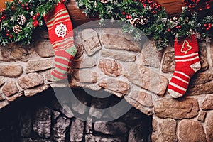 Christmas stockings hanging over a fireplace with candles on the mantlepiece.