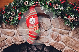 Christmas stockings hanging over a fireplace with candles on the mantlepiece.