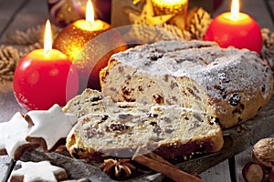 Christmas stollen with candles cinnamon stars cinnamon sticks pine twig nuts on wooden board