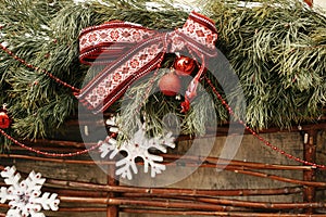 Christmas street decor. Stylish christmas snowy fir branches with festive red bow,snowflake, balls on window store at holiday