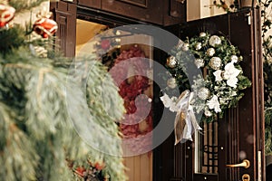 Christmas street decor. Stylish christmas wreath with silver ornaments on door at front store at holiday market in city street.