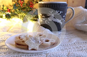 Christmas styled composition.Home made fresh baked Christmas cookies and mug of hot chocolate with marshmallow on a white woollen