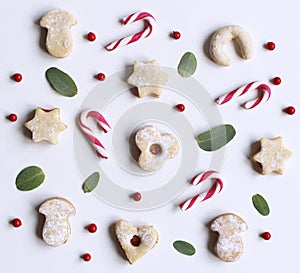 Christmas styled stock composition. Candy cane,homemade festive sweets and Eucalyptus leaves on white background. Flat