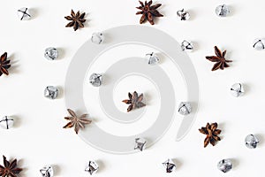 Christmas styled stock composition. Glittering silver jingle bells and anise stars on white background. Flat lay, top