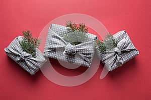 Christmas sustainable gifts wrapped in textile on red. Xmas. Japanese Furoshiki style. View from above. Flat lay.