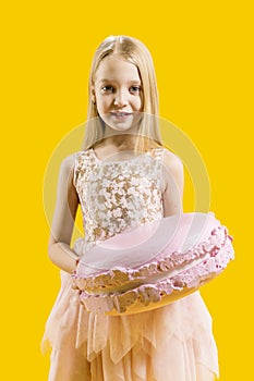 Christmas sweetness. Sweet gift. A cute girl is holding a huge pink macaroons on a yellow background. Round dessert