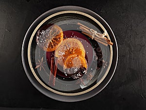 Christmas sweets, candied fruits in chocolate. Caramelized orange slices on a ceramic plate with spices and chocolate, black stone