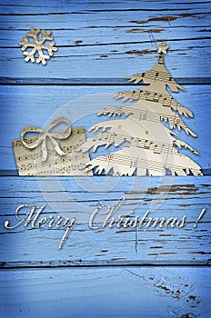 christmas symbol shapes cut from music sheets on blue wooden background