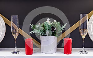 Christmas table decor with red candles, Christmas tree branches and champagne glasses