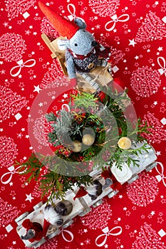 Christmas table decoration, including toy mouse on sled, elfes in wooden train and greenery in small vase