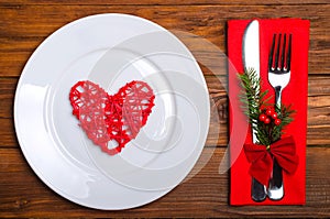 Christmas table: knife and fork, plate, napkin and Christmas tree branch on a wooden table top view with copy space.