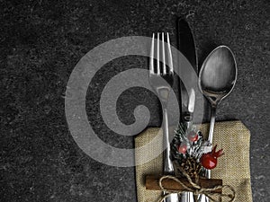 Christmas table place setting, cutlery in burlap bag with festive decorations star, cinnamon stick, pinecone with snow, berries,