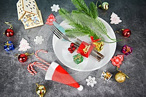 Christmas table place setting decoration with gift box ball candy cane in santa claus hat fork and knife plate Xmas New Year food