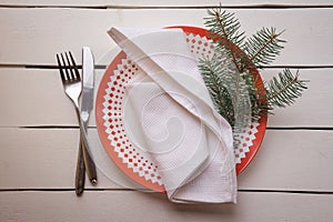 Christmas table place setting with dinner plates, napkin, cutlery, fir