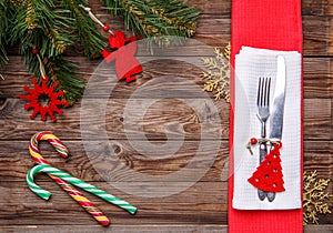 Christmas table place setting with fork and knife, decorated christmas toy - red fir-tree, christmas pine branches and