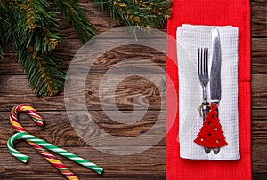 Christmas table place setting with fork and knife, decorated christmas toy - red fir-tree, two lollipop cane and christmas pine br