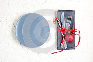 Christmas table place setting with napkin, fork, knife, ball, candy canes, plate. Christmas holidays background. Flat Lay, Top