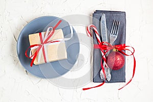 Christmas table place setting with napkin, fork, knife, ball, plate, candy canes and gift. Christmas holidays background. Flat Lay