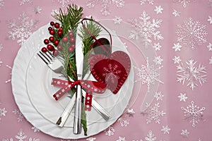 Christmas table place setting with pine branches,ribbon and bow.