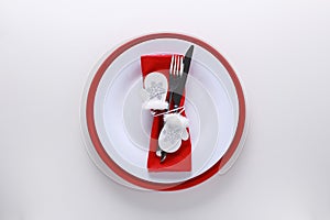 Christmas table place setting with red and white plates, knife, fork,napkin and wooden decoration mittens. Copy space,white